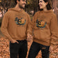 Two people wear matching brown "Halloween Town" hoodies with a pumpkin graphic.