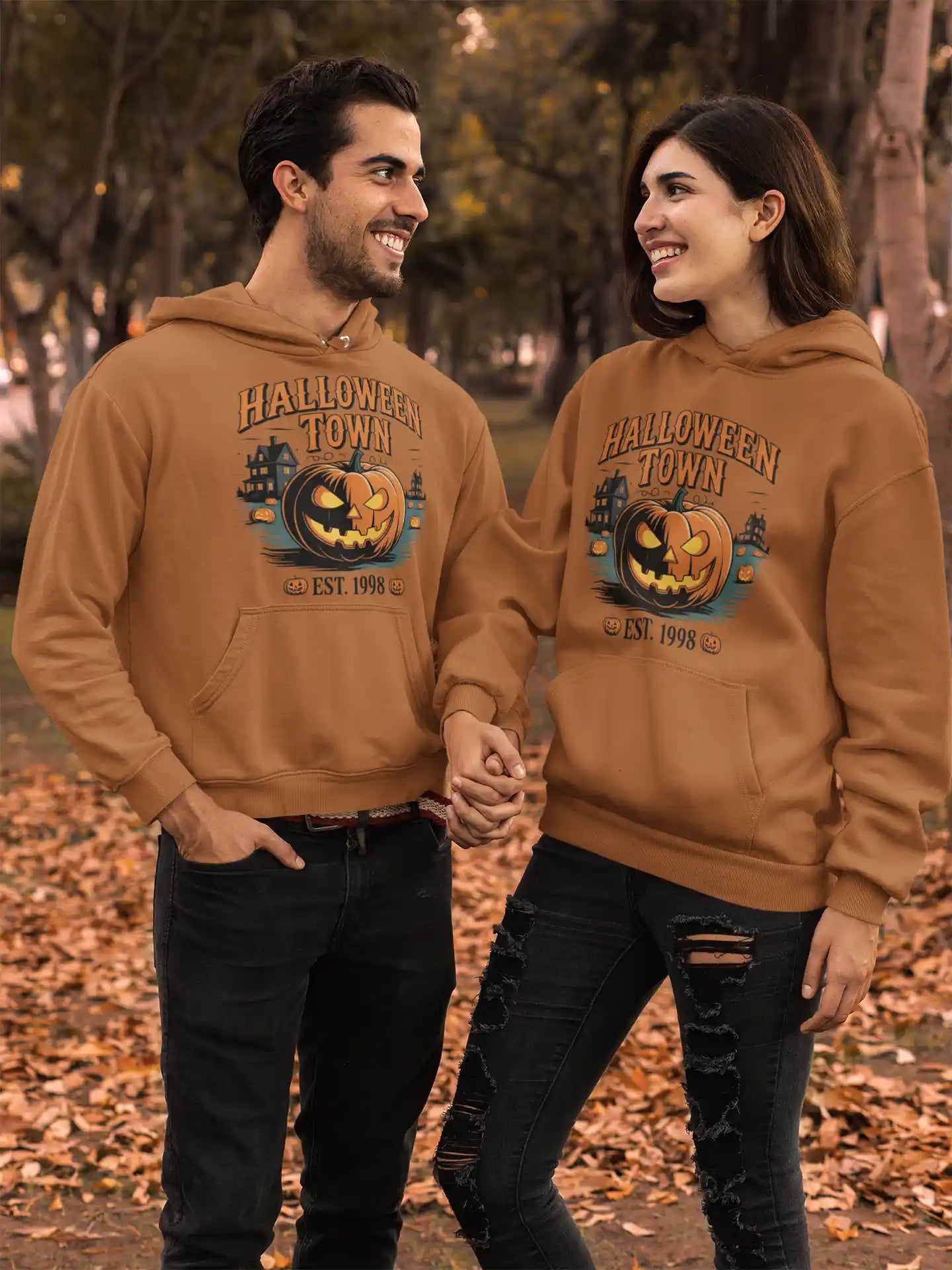 Two people wear matching brown "Halloween Town" hoodies with a pumpkin graphic.