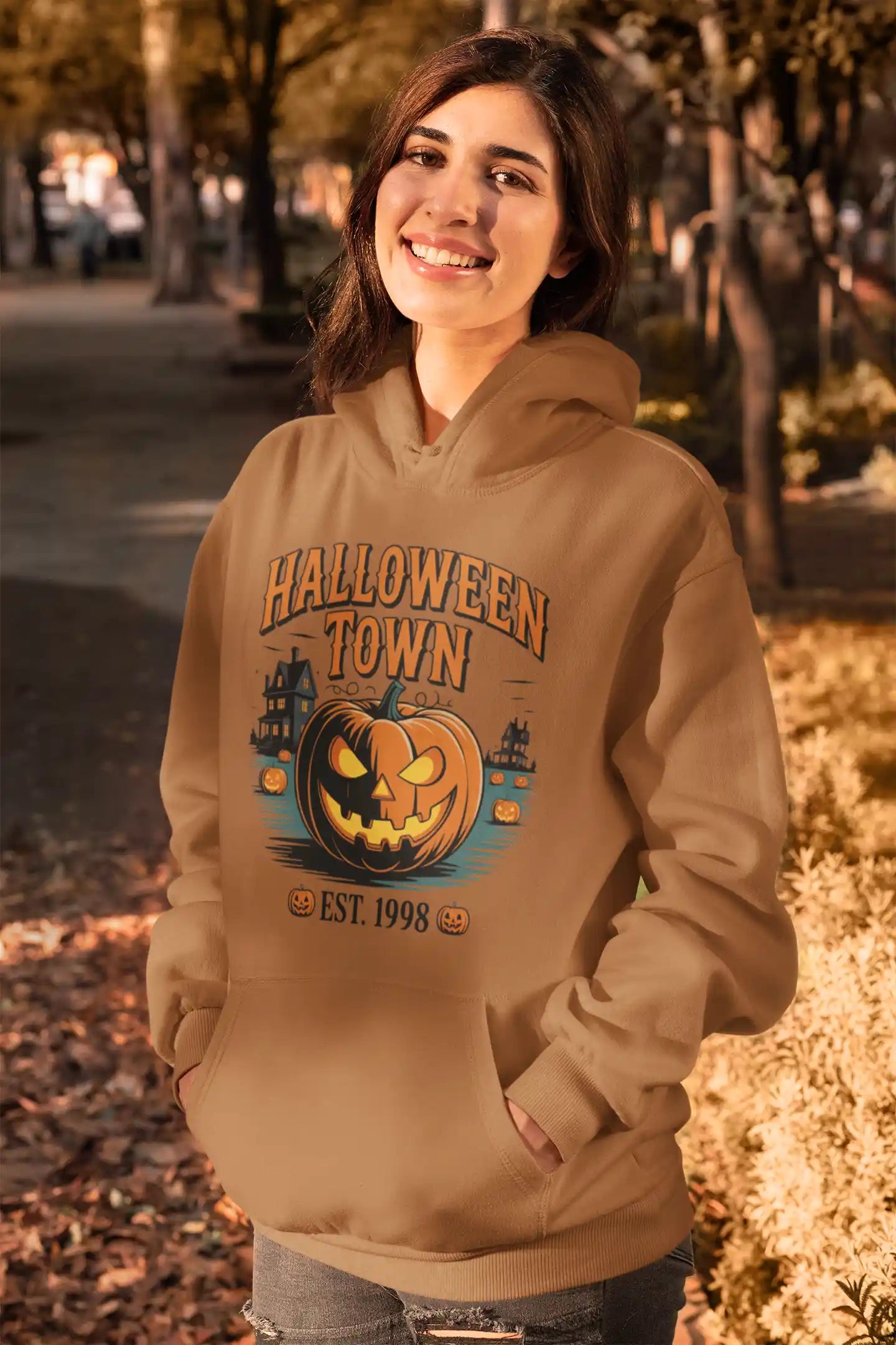 A woman smiles wearing a brown Halloween Town hoodie with a pumpkin graphic.