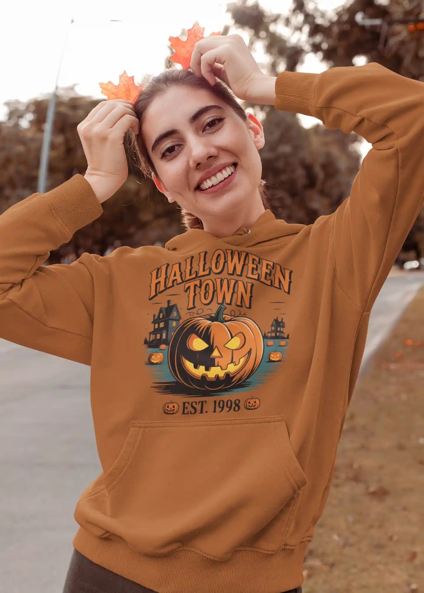 A woman wears a brown Halloween Town hoodie with a vintage pumpkin graphic.