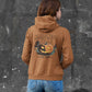 A person from behind wears a brown Halloween Town hoodie with a pumpkin graphic.