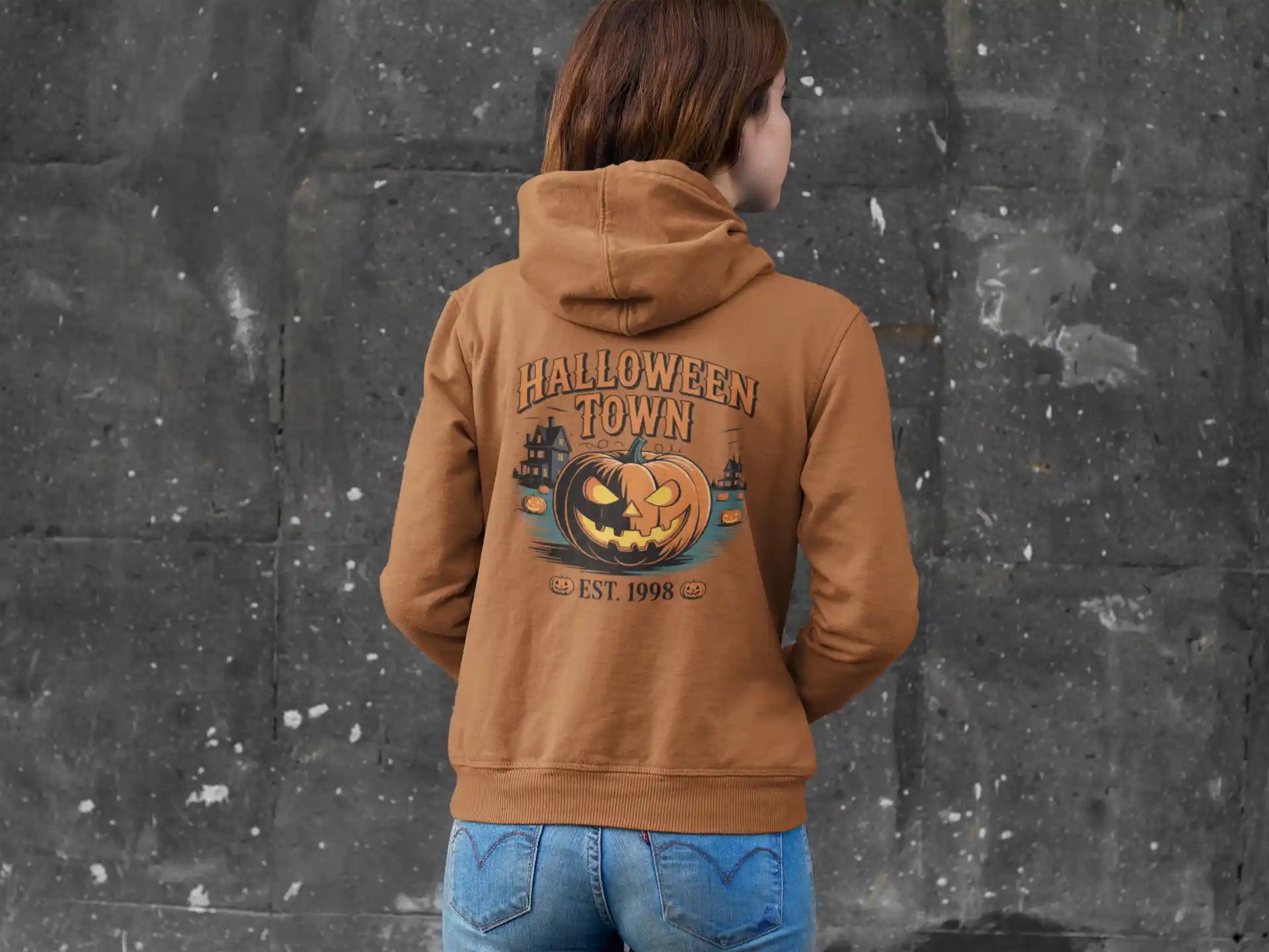A person from behind wears a brown Halloween Town hoodie with a pumpkin graphic.