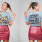 A woman models a light blue t-shirt with anime characters and a red leather skirt.