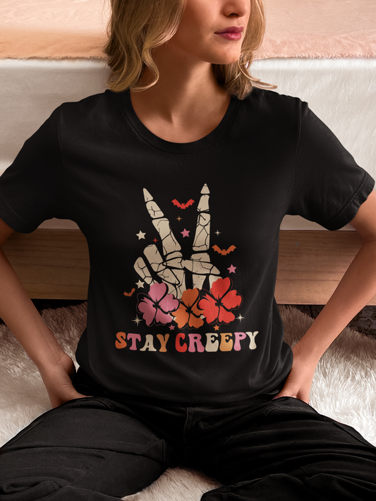 A woman wearing a black t-shirt with a skeleton peace sign and "Stay Creepy" text.