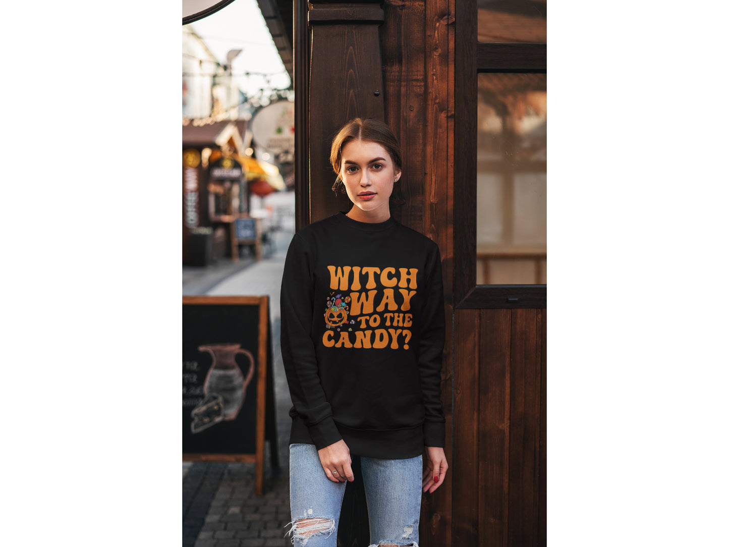 A woman wears a black "Witch Way to the Candy" Halloween sweatshirt.