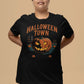 A woman wears a black Halloween Town t-shirt with a vintage pumpkin graphic.