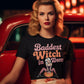A woman in a black "Baddest Witch in Town" t-shirt sits in a red car.