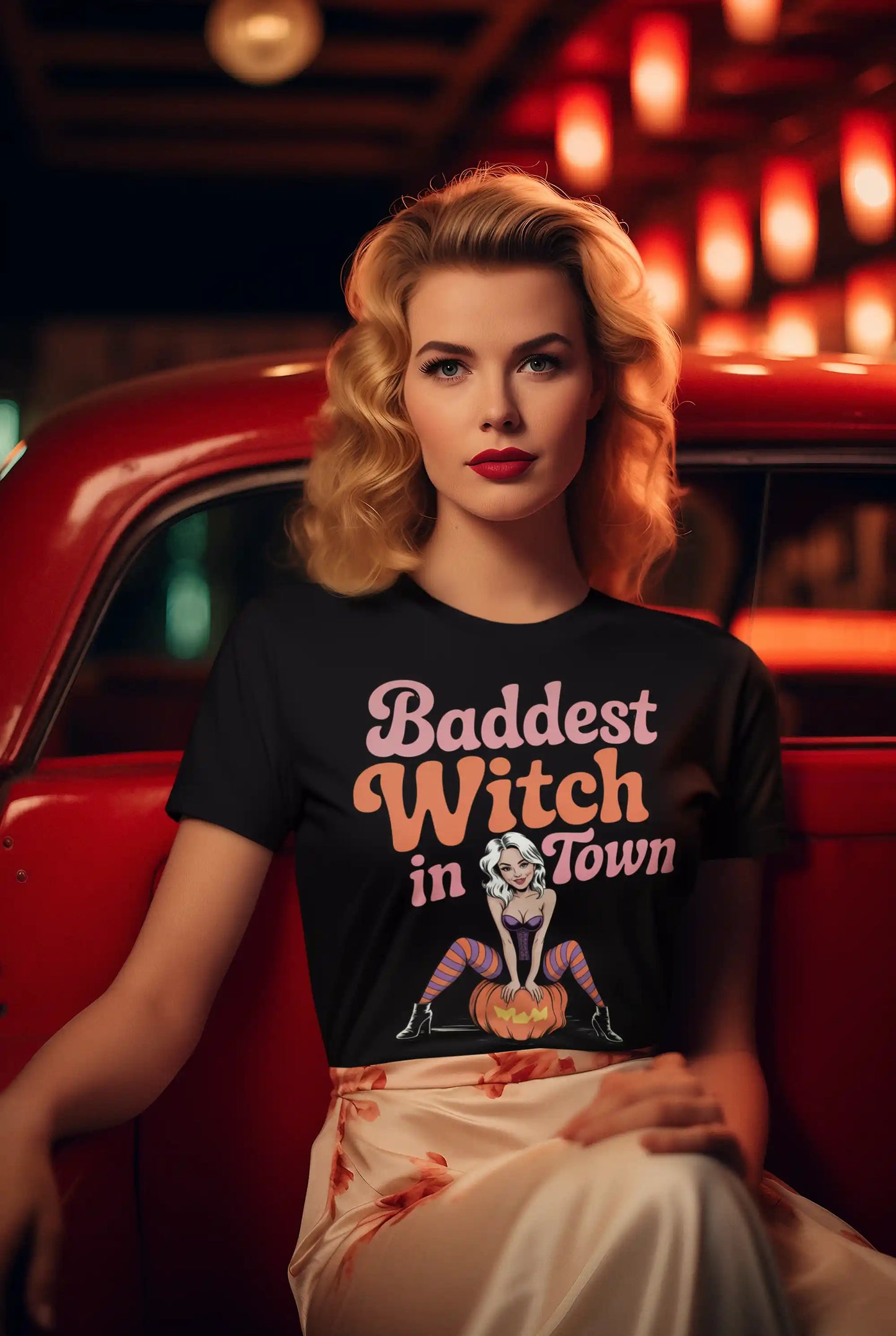 A woman in a black "Baddest Witch in Town" t-shirt sits in a red car.