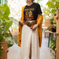 A woman wears a black t-shirt with a Halloween duck graphic, a long white skirt, and a yellow cardigan.