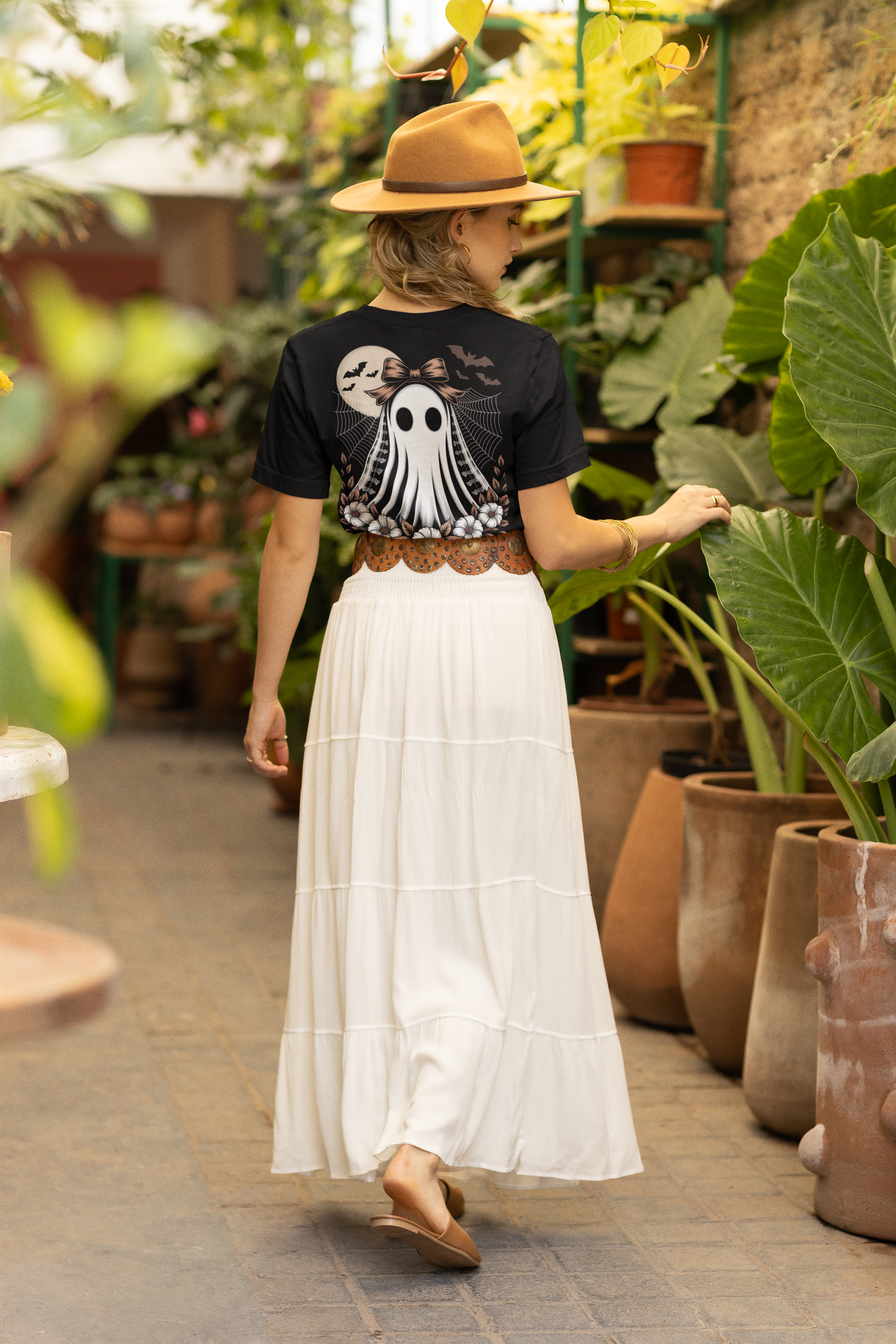 A woman from behind wears a black t-shirt with a ghost design and a long white skirt.