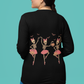 A woman from behind wears a black long-sleeve shirt with dancing skeleton ballerinas.