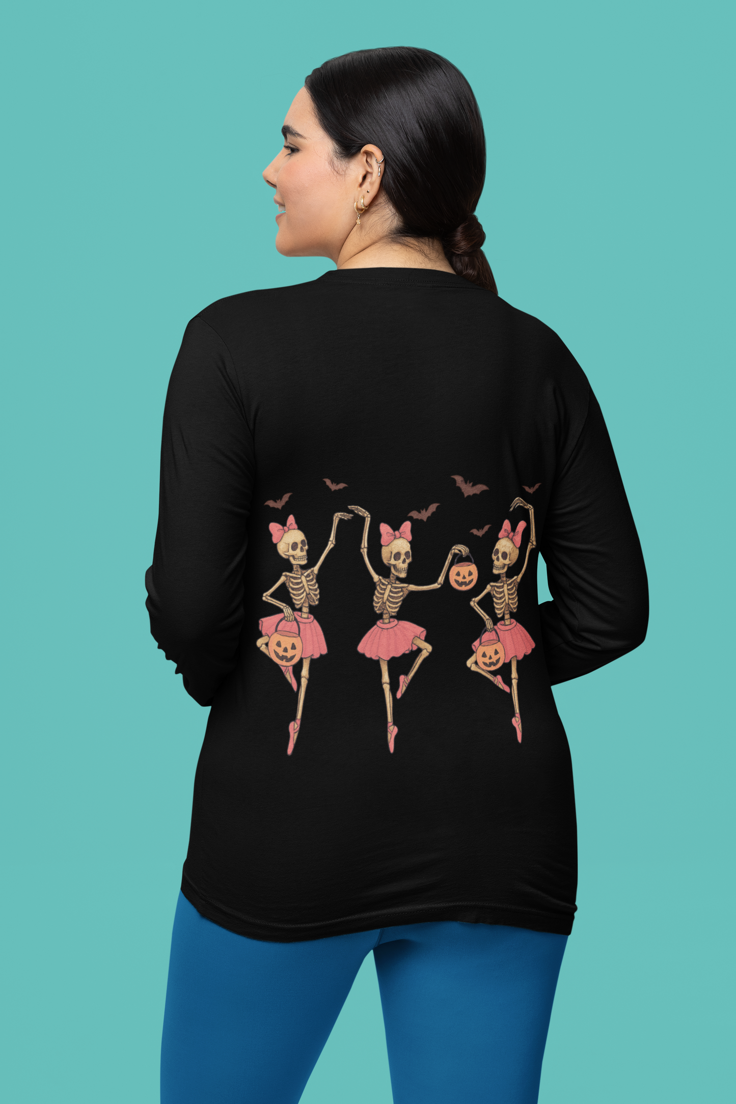A woman from behind wears a black long-sleeve shirt with dancing skeleton ballerinas.