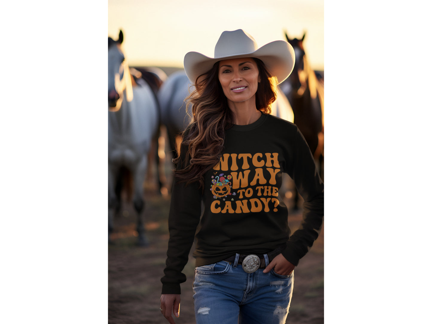 A woman in a black "Witch Way to the Candy" Halloween sweatshirt stands with horses.
