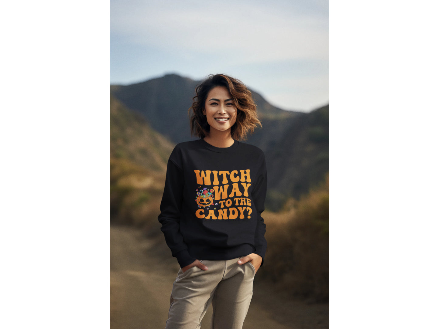 A woman smiles wearing a black "Witch Way to the Candy" Halloween sweatshirt.