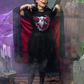 A woman in a ghost t-shirt, black skirt, and cape poses in a Halloween setting.