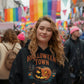 A woman wears a black Halloween Town hoodie with a vintage pumpkin graphic.