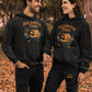 Two people wear black Halloween Town hoodies with a vintage pumpkin graphic.