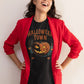 A woman in a red blazer laughs while wearing a black Halloween Town t-shirt.