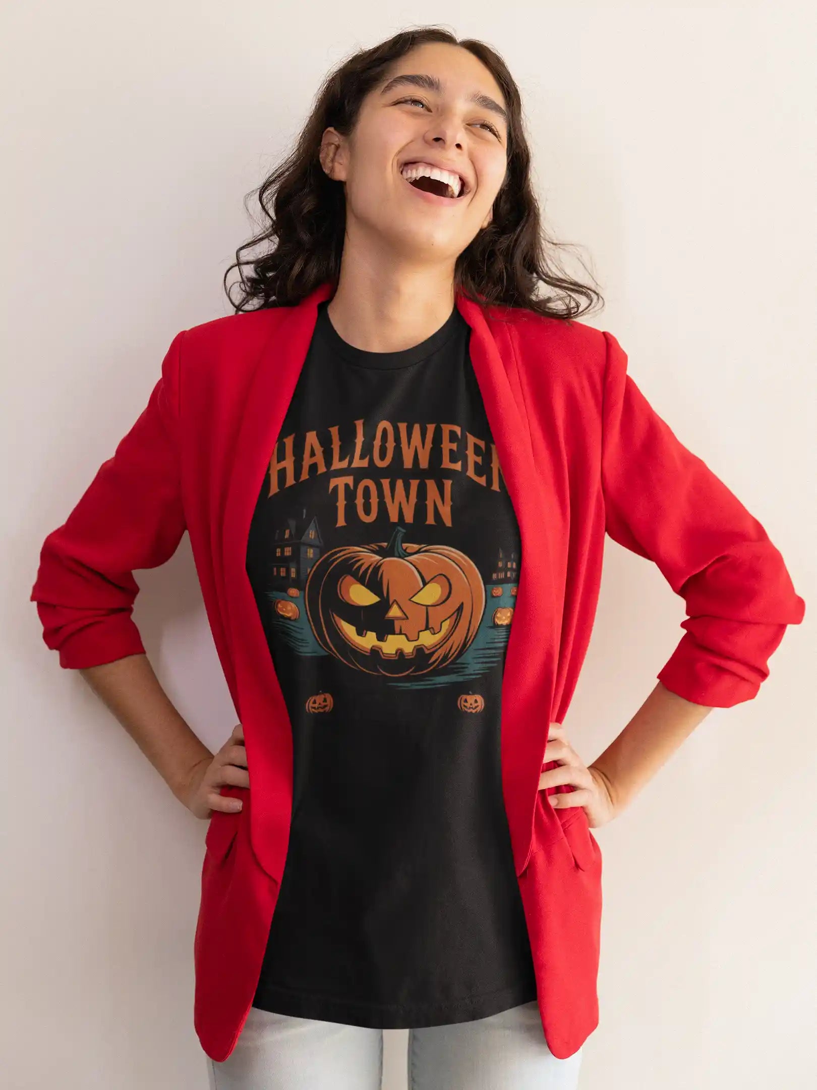 A woman in a red blazer laughs while wearing a black Halloween Town t-shirt.