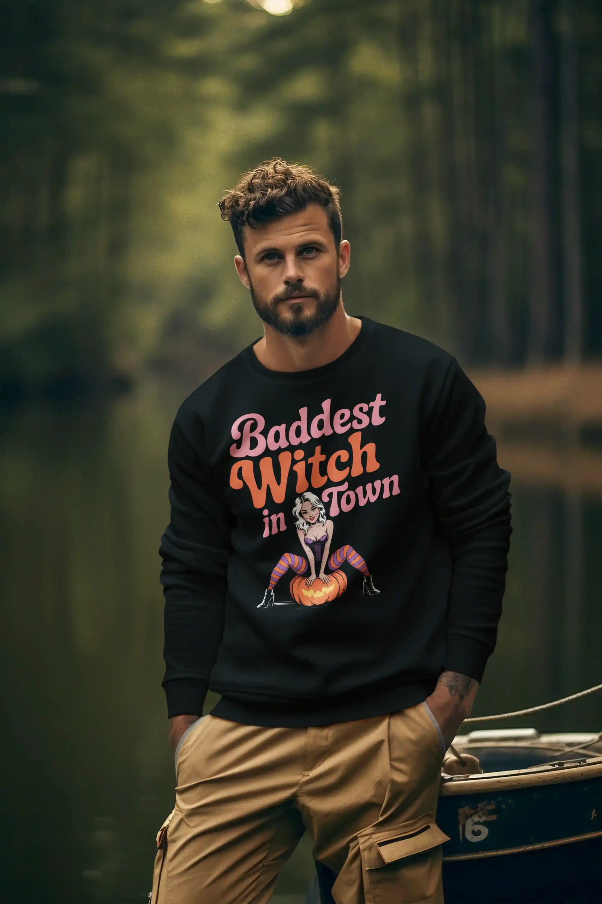 A man wears a black sweatshirt with "Baddest Witch in Town" and a witch graphic.