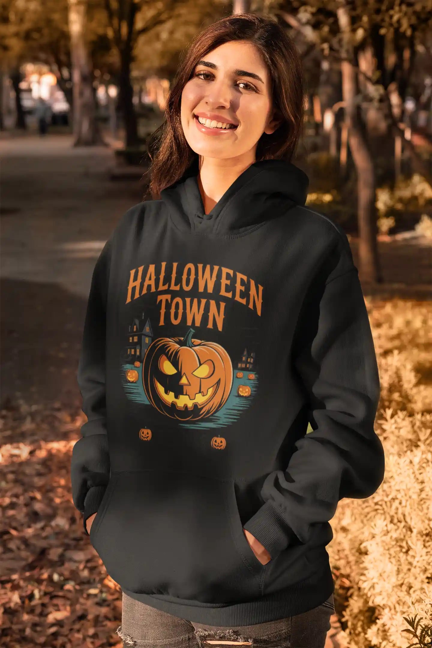 A woman smiles while wearing a black Halloween Town hoodie with a pumpkin graphic.