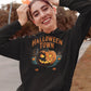 A woman smiles while wearing a black Halloween Town hoodie with a pumpkin graphic.