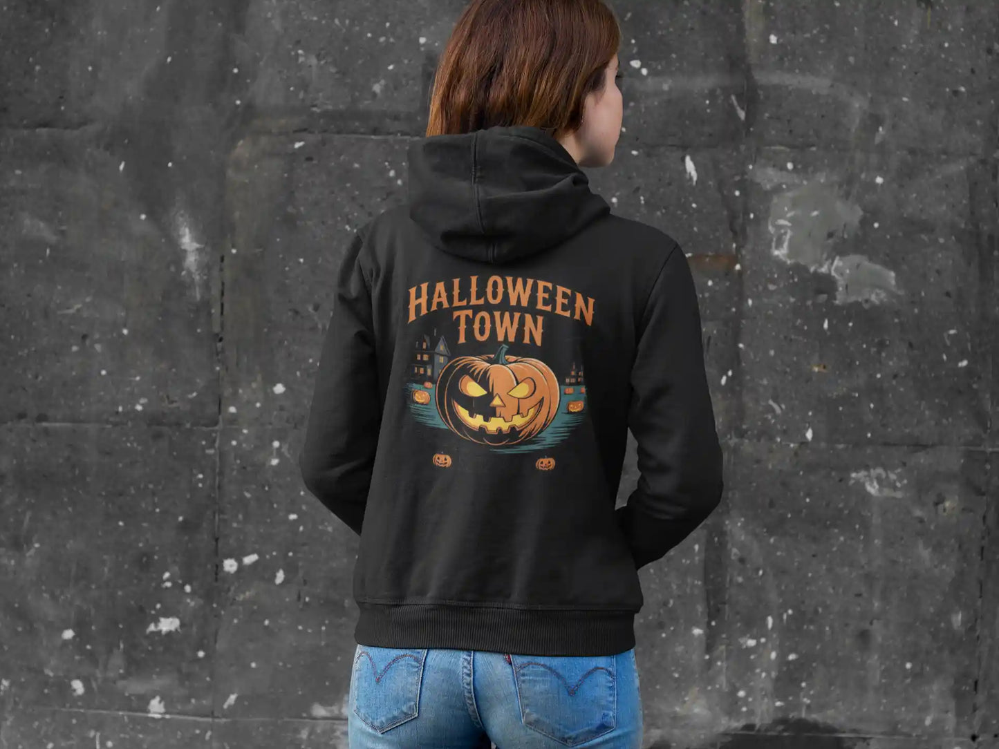 A person from behind wears a black Halloween Town hoodie with a vintage pumpkin graphic.
