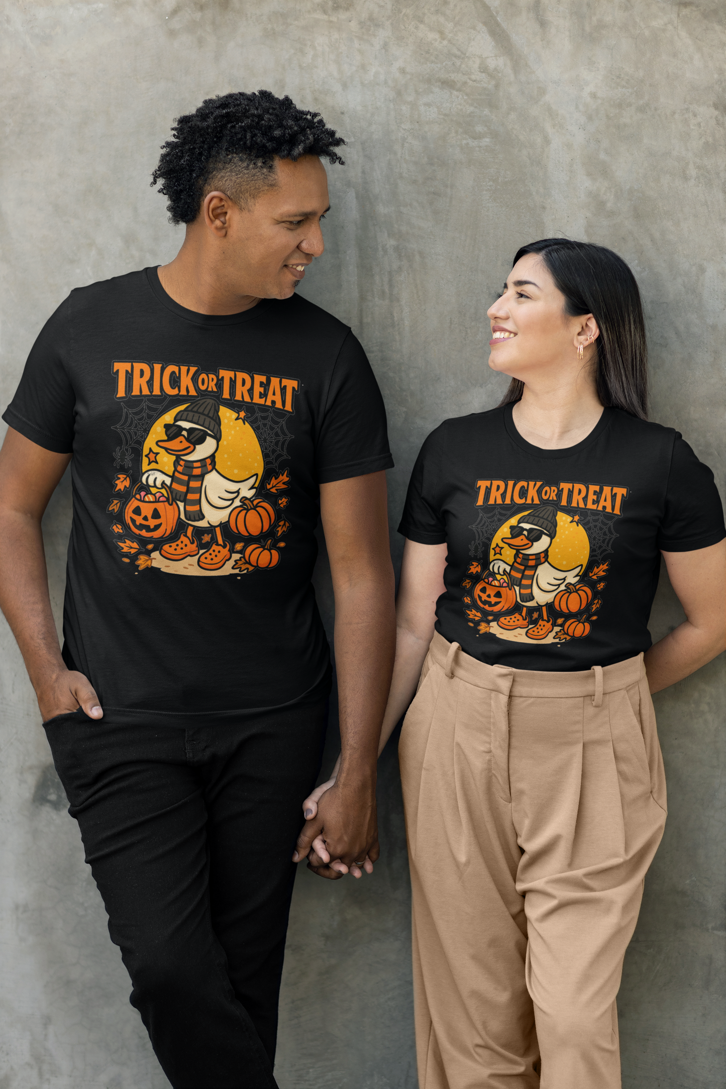 A couple wearing black Halloween duck graphic t-shirts, holding hands.