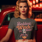 A woman in a gray "Baddest Witch in Town" t-shirt sits in a red car.