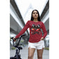 A woman wears a red long-sleeve shirt with a spooky cherry and bow design.