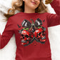 A woman wears a red long-sleeve shirt with a spooky cherry and skull design.