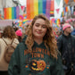 A woman wears a dark green Halloween Town hoodie with a pumpkin graphic.