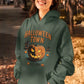 A woman smiles while wearing a green Halloween Town hoodie with a pumpkin graphic.
