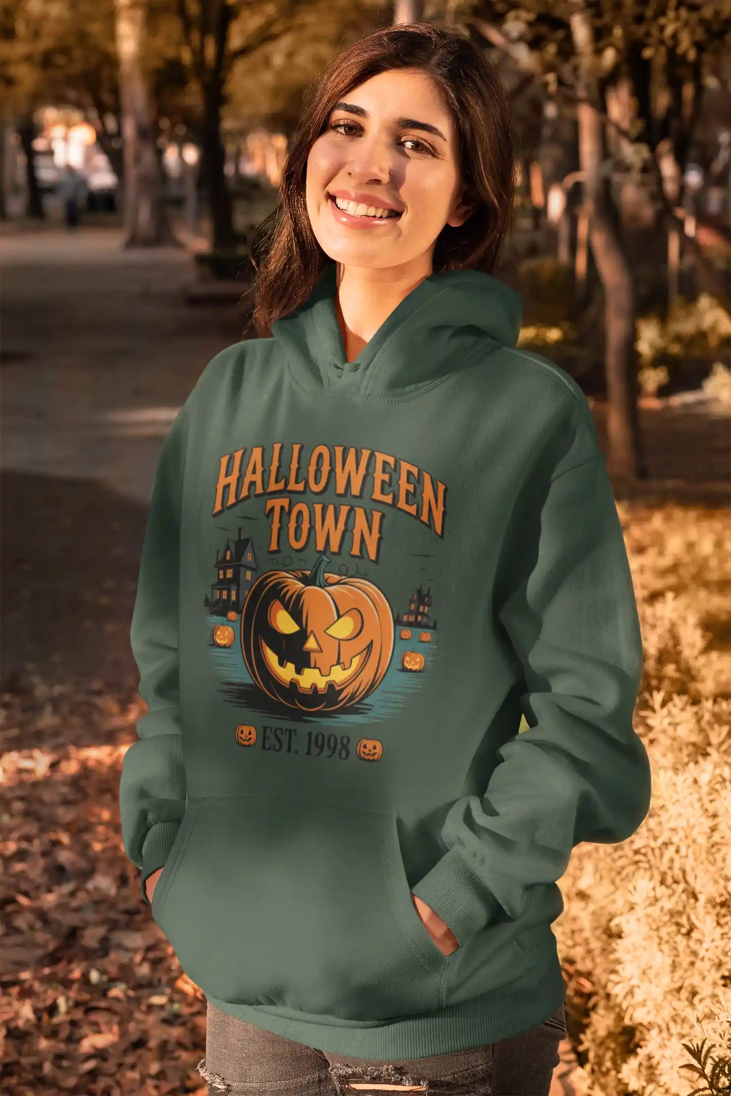 A woman smiles while wearing a green Halloween Town hoodie with a pumpkin graphic.