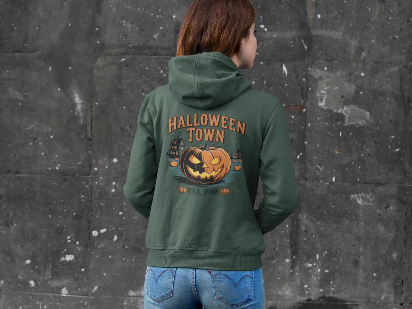 A person from behind wears a military green Halloween Town hoodie with a pumpkin graphic.