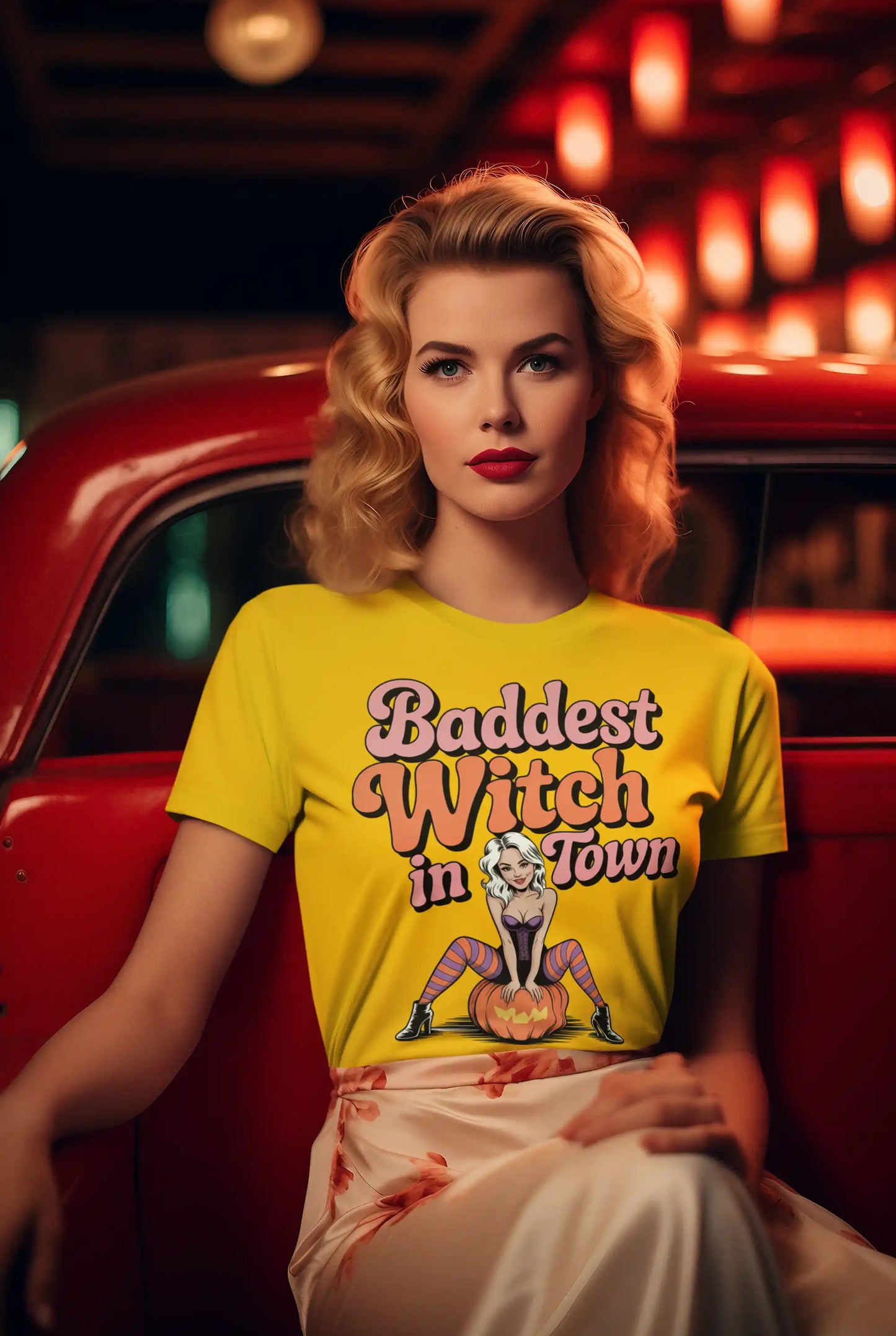 A woman in a yellow "Baddest Witch in Town" t-shirt sits in a red car.
