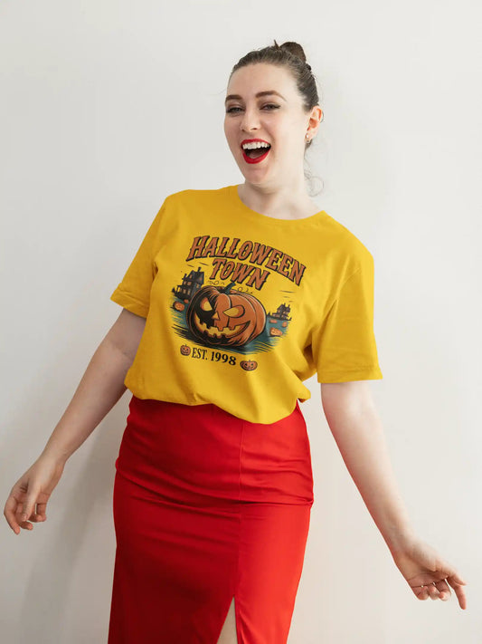 A woman smiles wearing a yellow Halloween Town t-shirt with a pumpkin graphic.