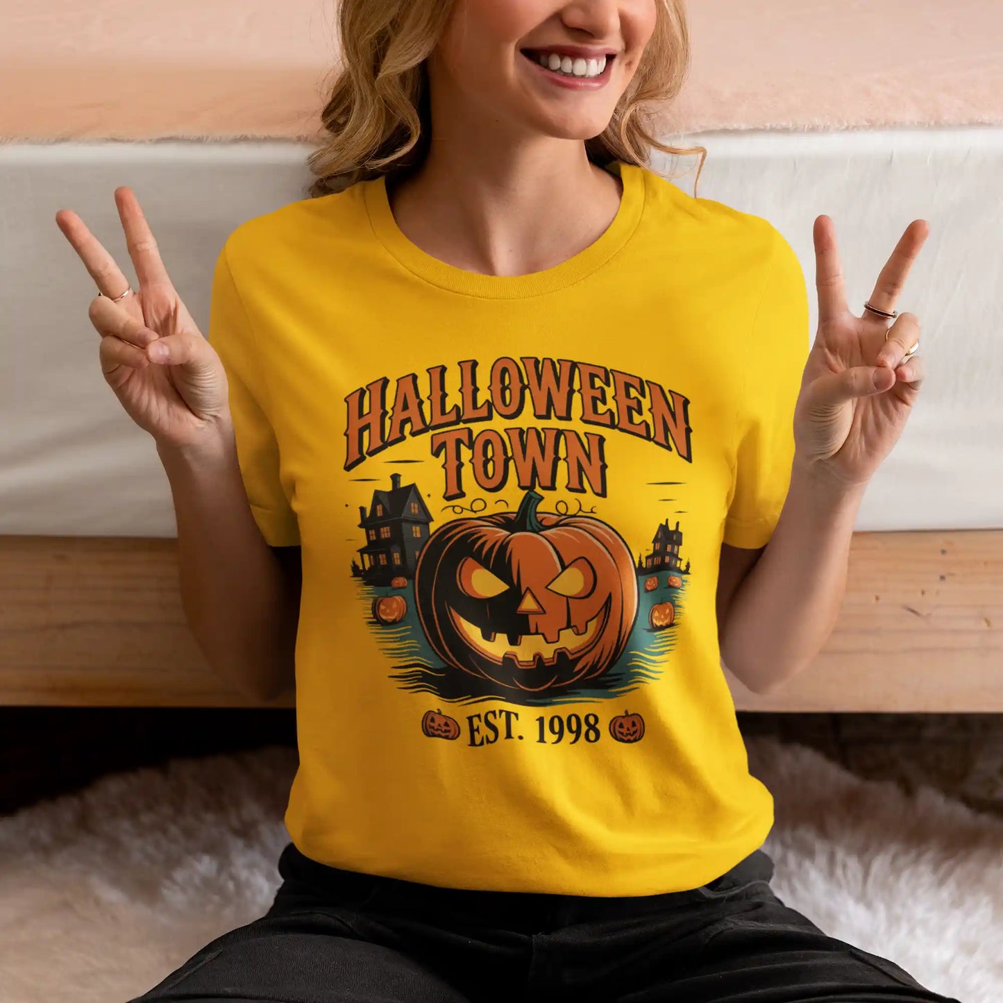 A person wears a yellow Halloween Town t-shirt with a vintage pumpkin graphic.