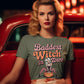 A woman in a green t-shirt with "Baddest Witch in Town" graphic sits in a red car.
