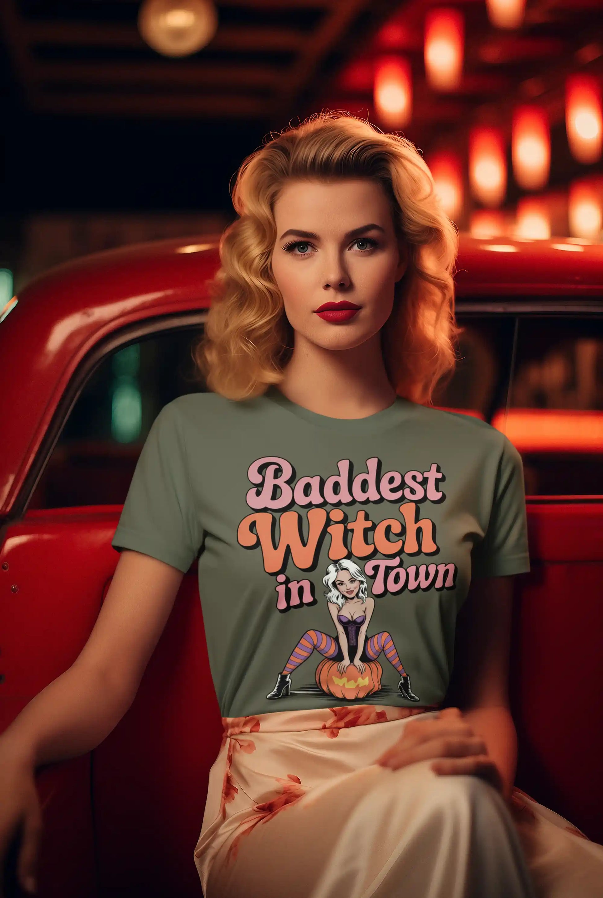 A woman in a green t-shirt with "Baddest Witch in Town" graphic sits in a red car.