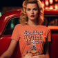A woman with blonde hair and red lipstick wears an orange "Baddest Witch in Town" t-shirt.