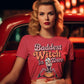 A woman in a pink "Baddest Witch in Town" t-shirt sits in a red car.