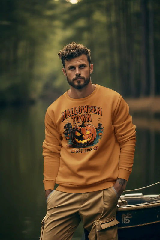 A man wears an orange Halloween Town sweatshirt with a pumpkin graphic and khaki pants.