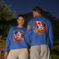 Two people wear blue long-sleeve sweatshirts with Canadian Halloween designs.