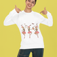A woman in a white long-sleeve shirt with dancing skeleton ballerinas and jeans.