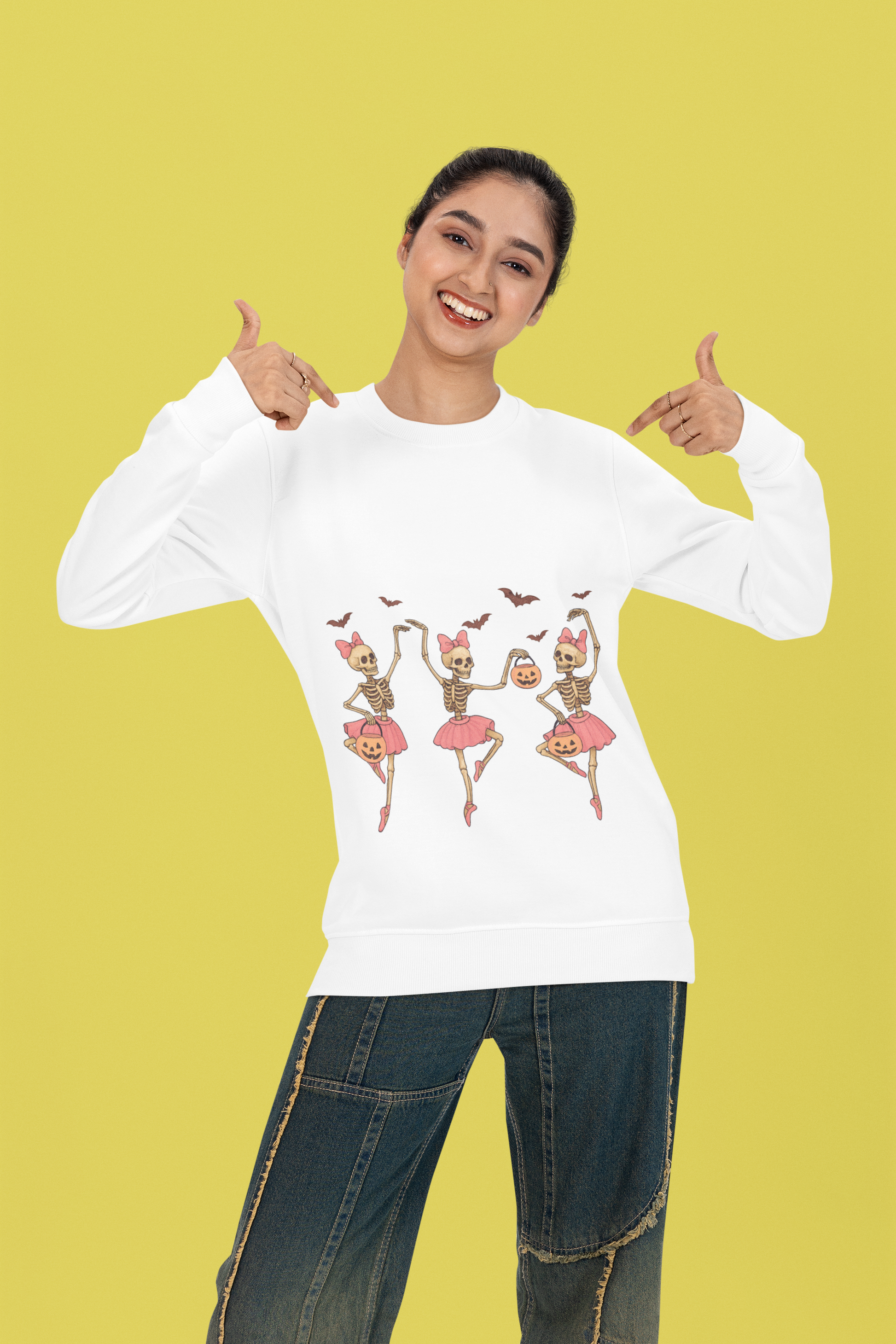 A woman in a white long-sleeve shirt with dancing skeleton ballerinas and jeans.