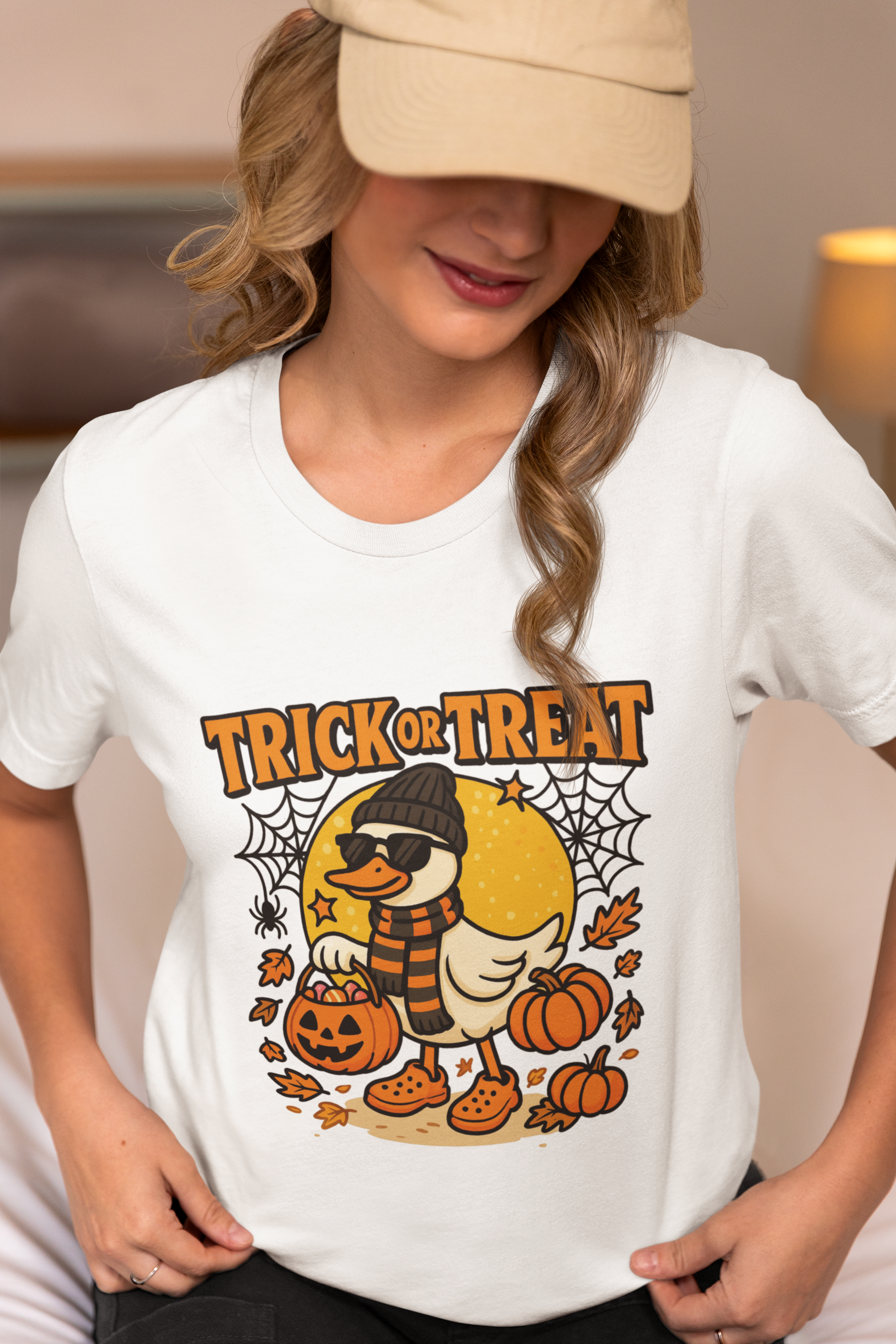 A woman in a beige cap and white t-shirt with a Halloween duck graphic.