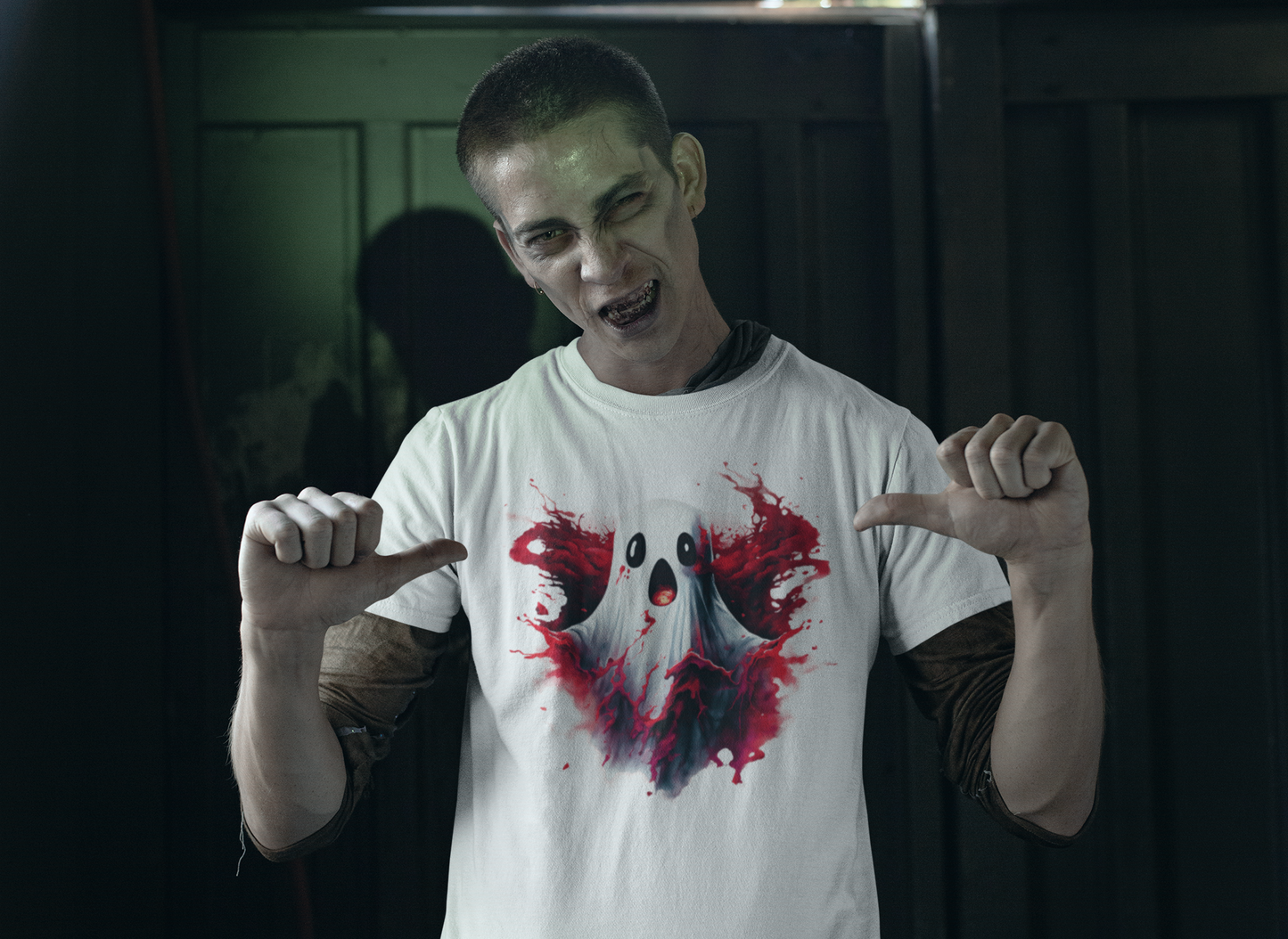 A zombie-like man points to a white t-shirt with a ghost and red splatters.