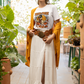 A woman wears a white Halloween duck t-shirt, a long white skirt, and a mustard cardigan.