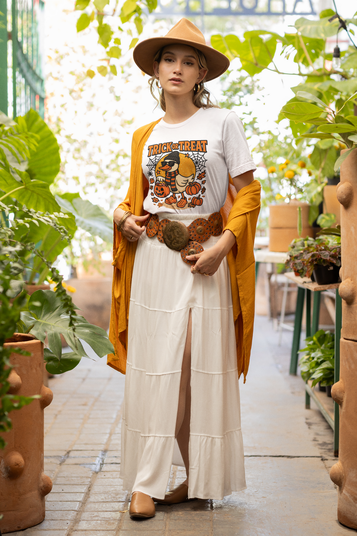 A woman wears a white Halloween duck t-shirt, a long white skirt, and a mustard cardigan.